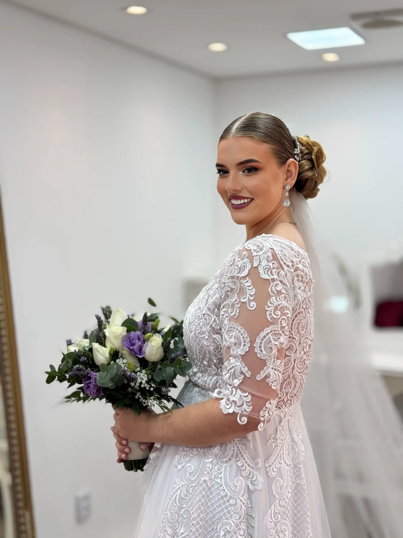 Noiva de vestido rendado com buquê, penteado e maquiagem feitos no Millenium